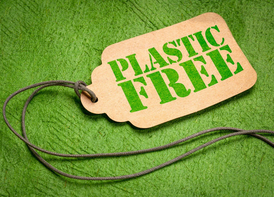 Brown tag with green PLASTIC FREE text on green textured background, eco-friendly concept