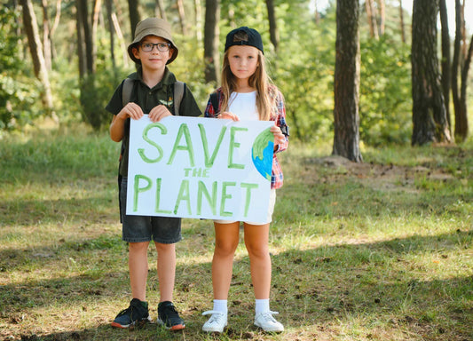 Kids holding Save the Planet sign in forest, environmental conservation awareness